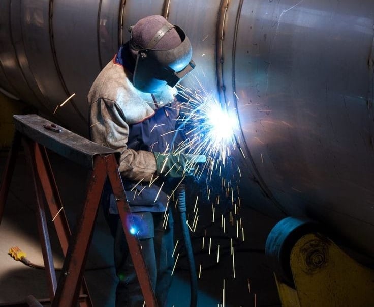 a man welding a pipehead in a factory
