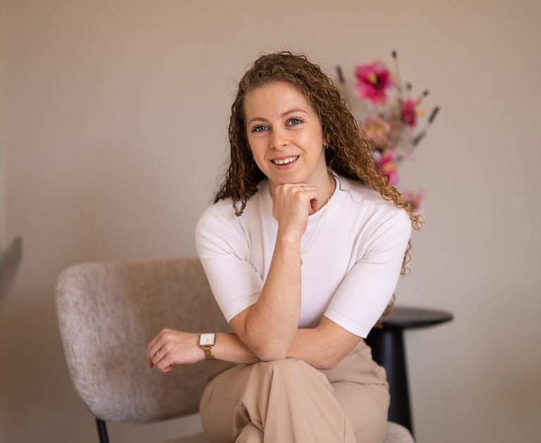 a woman (the owner) sitting in a chair with a flower in the background