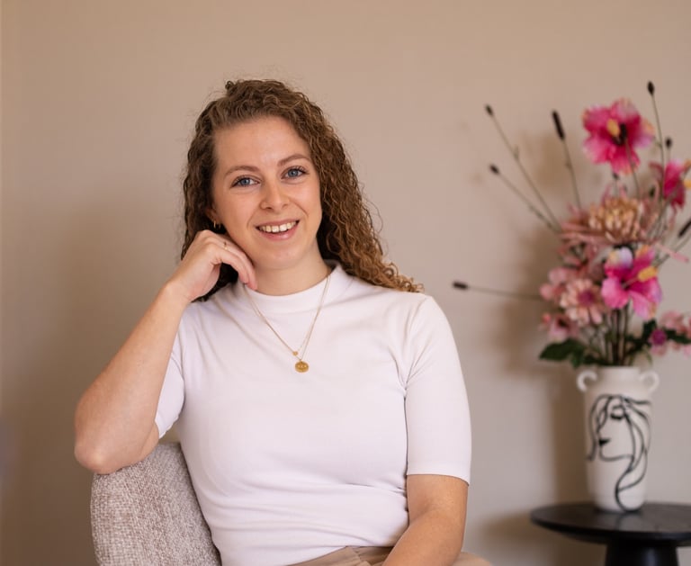 a woman, the writher, sitting in a chair with a flower in the background