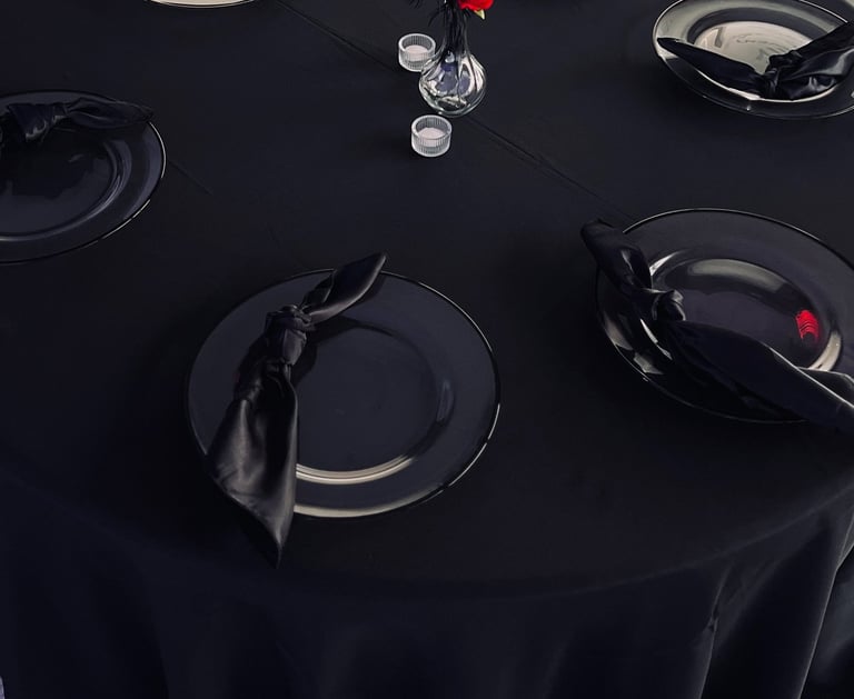Table ronde élégante pour avec une nappe noire, des assiettes de présentation, des serviettes.