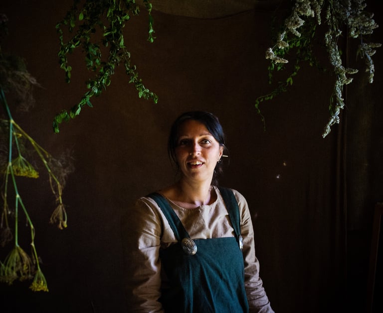 an atmospheric picture of a woman in green viking clothes surrounded by herbal plants
