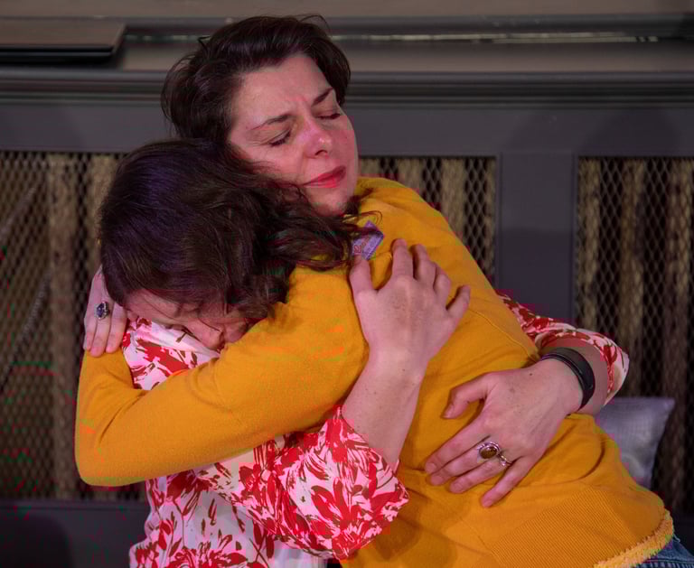 A mother and her preteen daughter embrace tightly, their eyes closed.