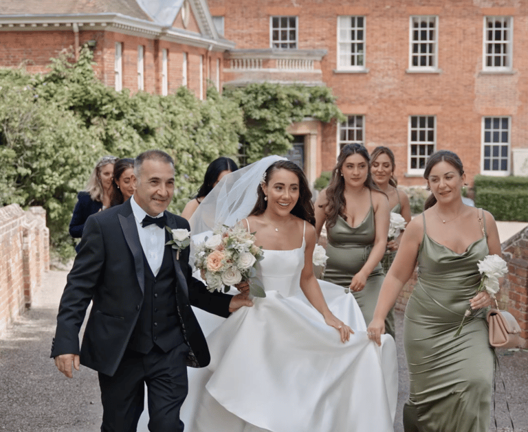 bride and father along with bridesmaids walking towards the the ceremony