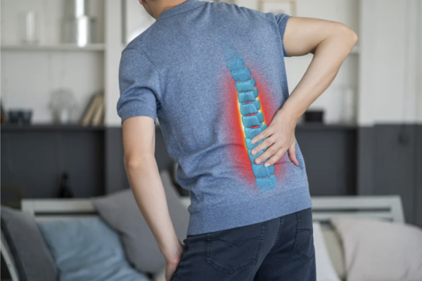 A man holding his lower back with a glowing 3D spine graphic representing chronic back pain and injury.