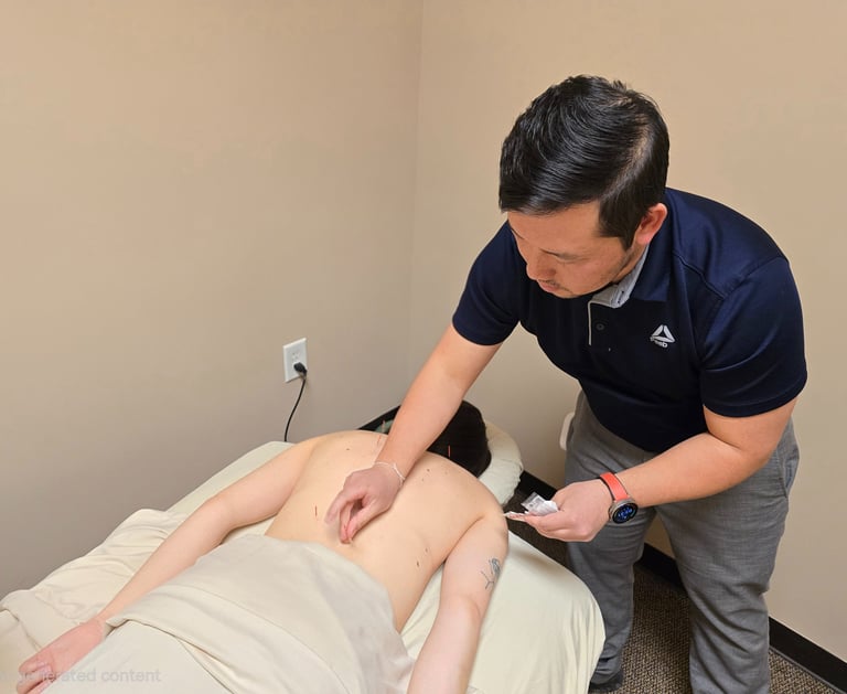 Dr. Xiong performing acupuncture with fine needles placed in patient’s back for pain relief therapy