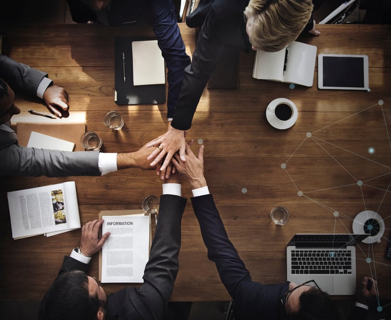 Overhead view of a business team joining hands over a boardroom table for a successful partnership.