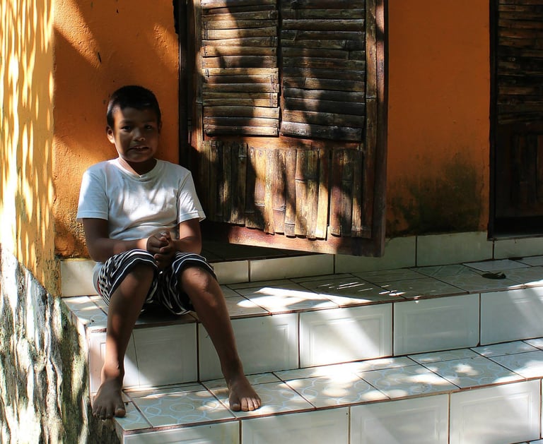 a young boy sitting on the steps of a house in Puerto Vallarta