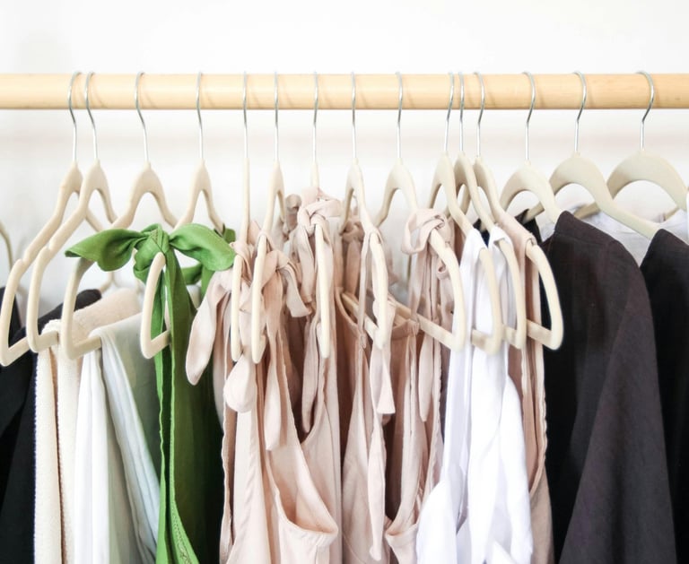 Organized clothing rack featuring a selection of neutral linen-toned tops.