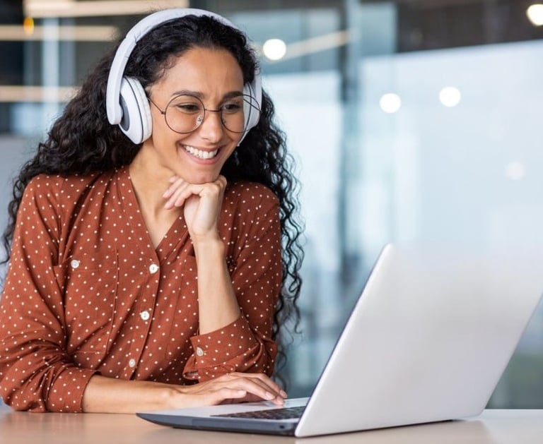 Young woman with headset smiling at laptop