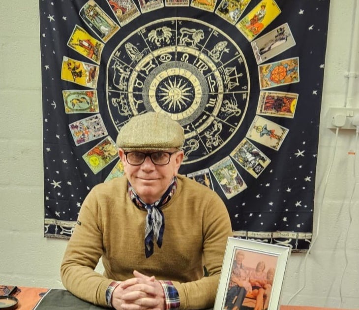 Rob hamilton 4th generation Romani reader, sitting down, astrological signs behind him