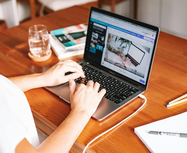 a woman sitting at a table with a laptop and a glass of wine
