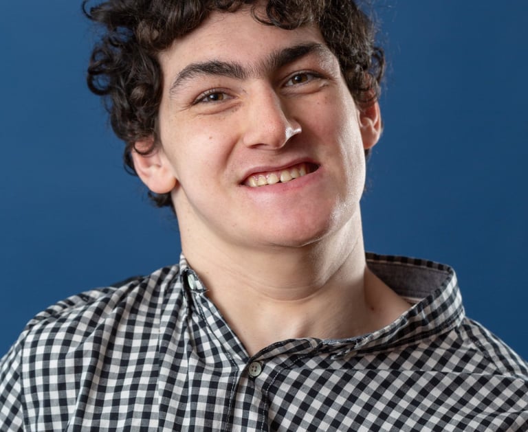 Artist Big Ody has brown curly hair and is smiling at the camera. 