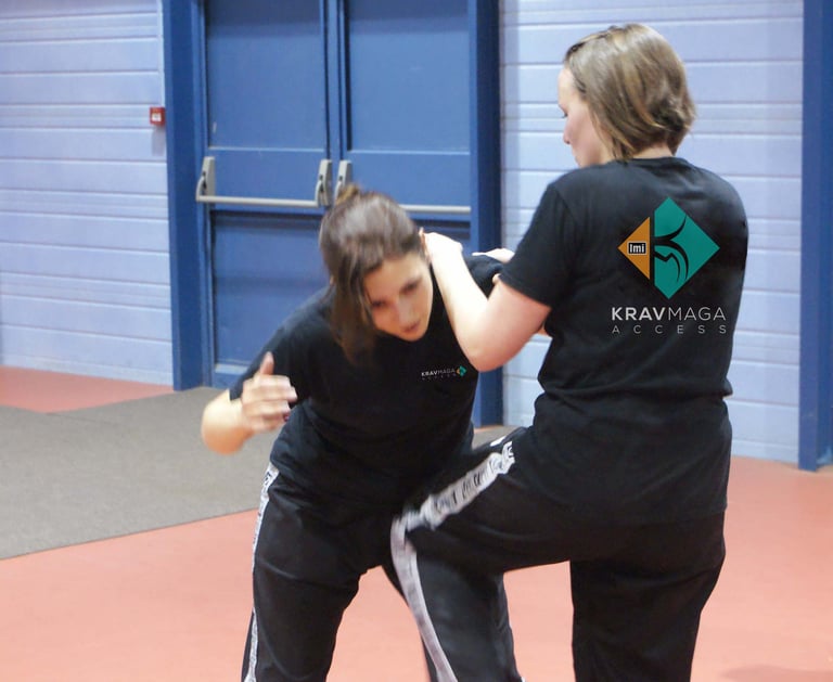 a woman in black shirt and pants standing in a room practice krav maga