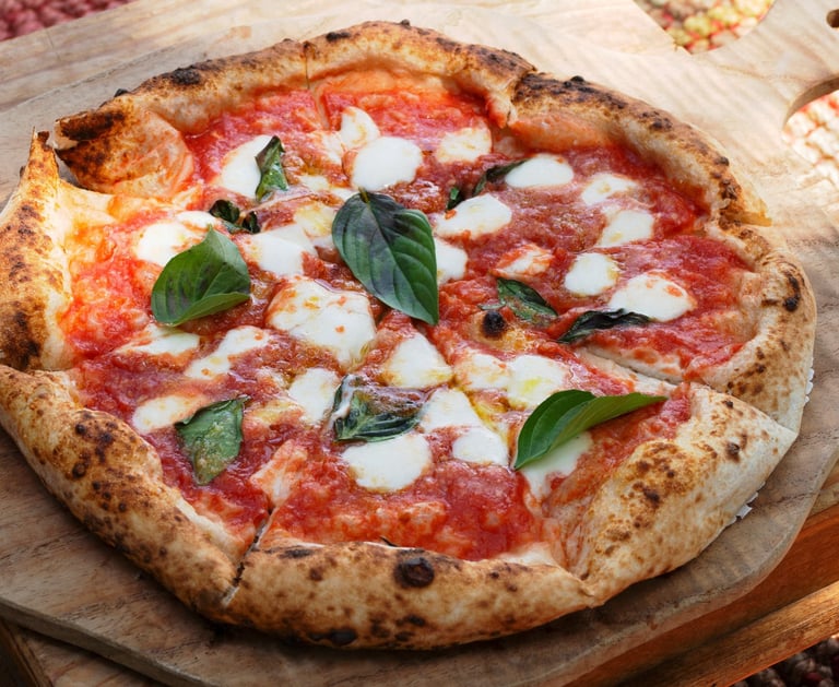 eine neapolitanische Pizza mit Mozarella und Basilikum auf einem Holzbrett