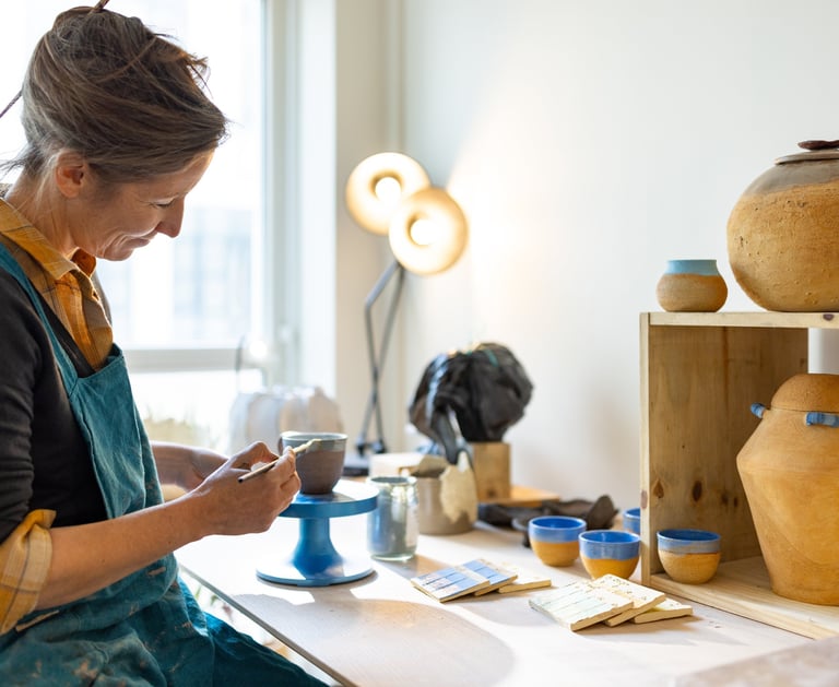 estelle del céramiste dans son atelier tourangeaux posant de l'engobe sur une tasse en céramique
