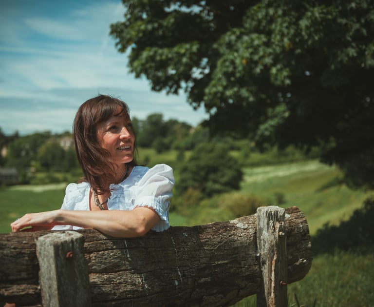 a woman sitting on a bench in a field