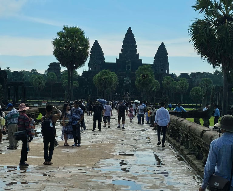 Visitors walking along the main stone pathway to Angkor Wat in Cambodia on a clear day