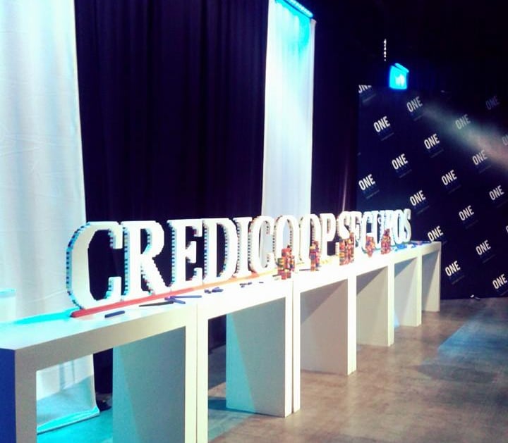 a man standing in front of a sign that says creditocoop seguros rasti corporasti