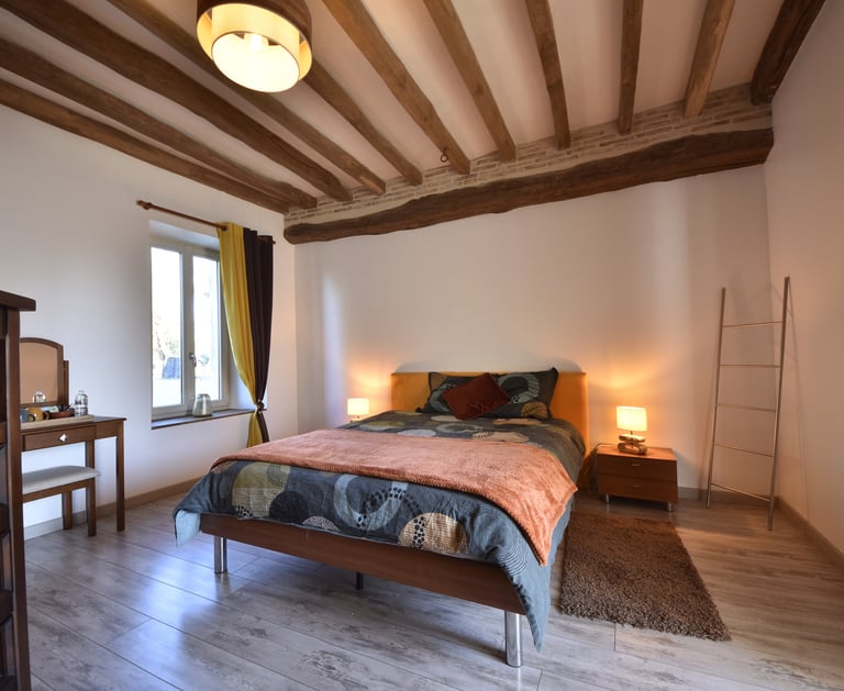 chambre lit double, poutres apparentes et briques