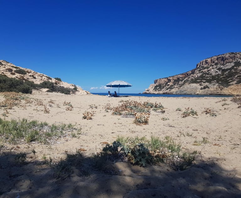 A couple under an umbrella on a beach in Antiparos island
