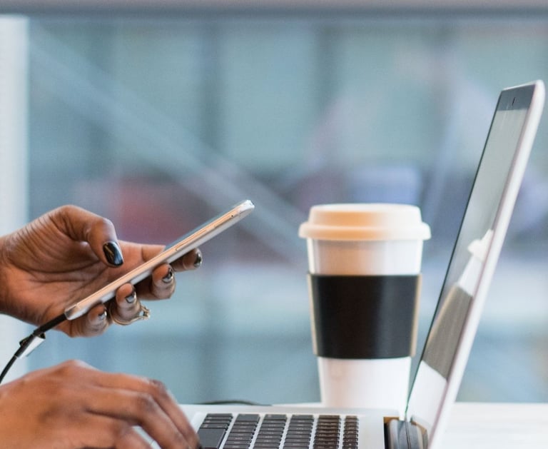 a person sitting at a table with a laptop and a cell phone