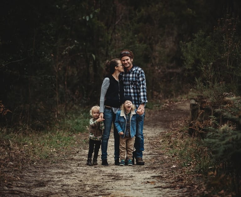 a family of four standing on a path in a wooded area