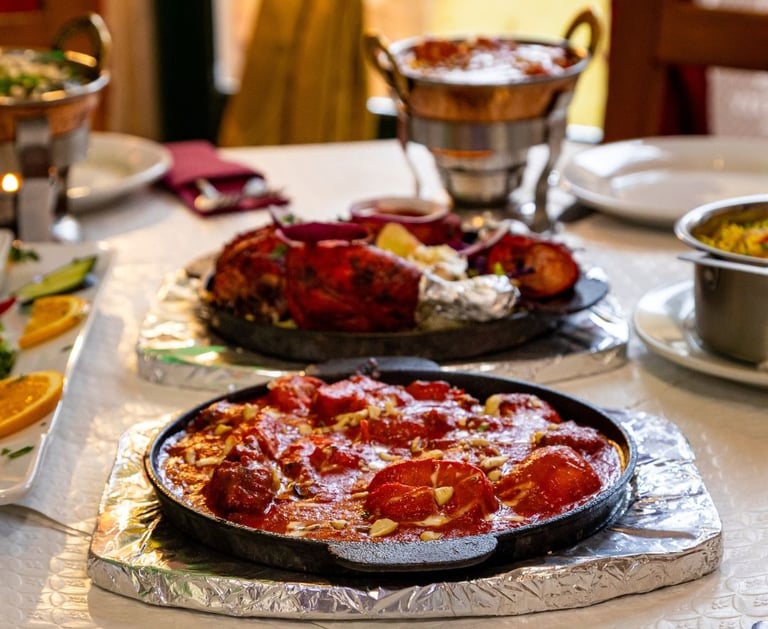 Sizzling authentic Indian butter chicken and tandoori chicken served on hot plates at a restaurant table.