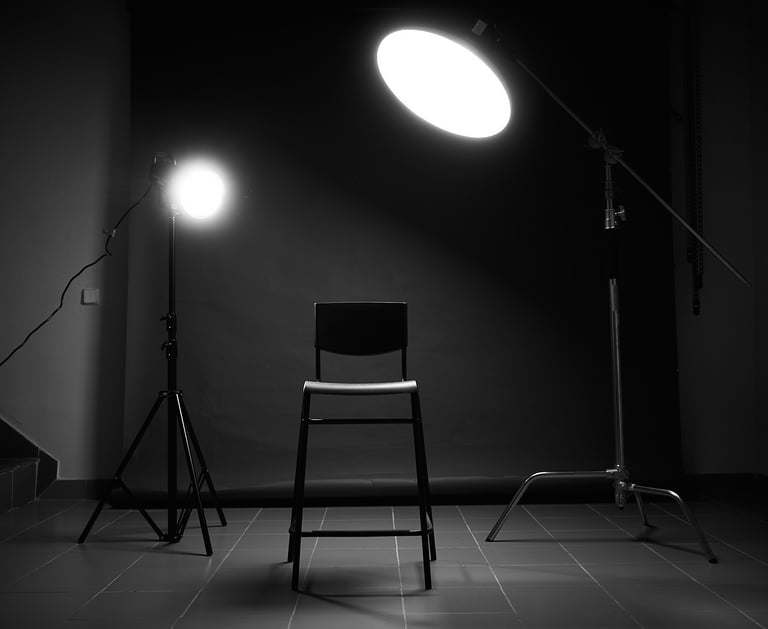 Professional photography studio setup with a chair under bright studio lights and black background.