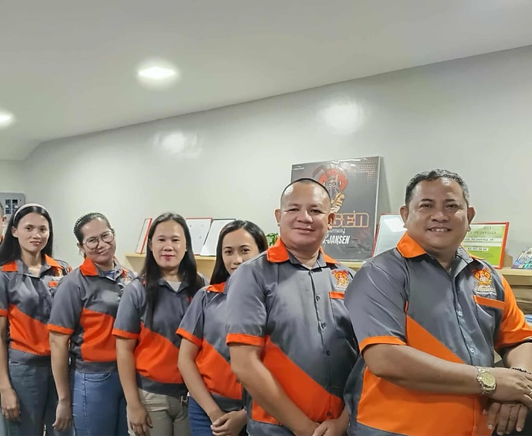 A team of professional employees posing together in matching orange and grey company uniforms.