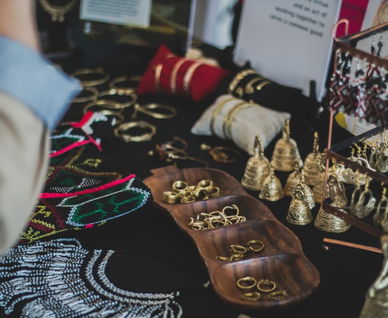 Exhibición de joyas hechas a mano con anillos, brazaletes y aretes étnicos en un mercado.