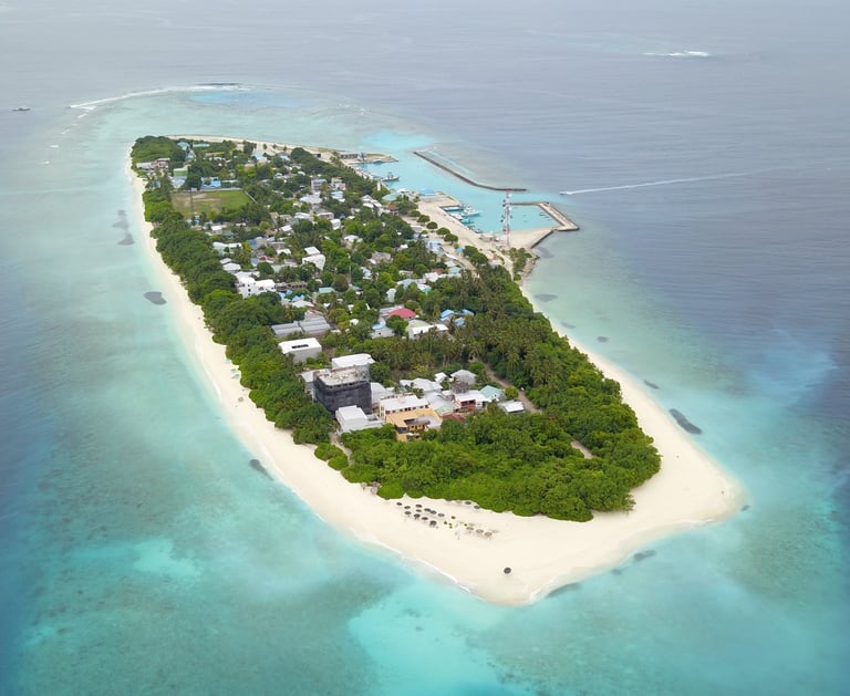 Aerial view of a tropical Maldives island with white sand beaches and turquoise coral reefs.