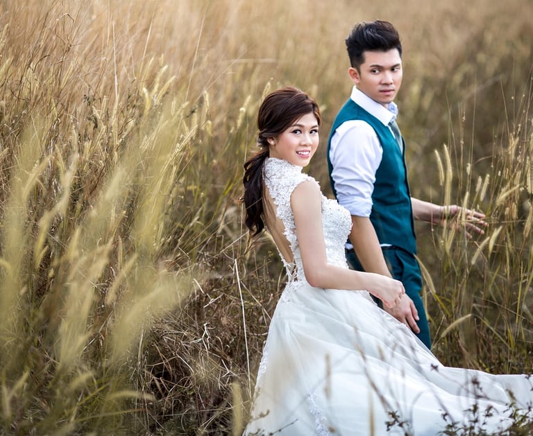 A man and woman standing in tall grass in wedding dress and suit