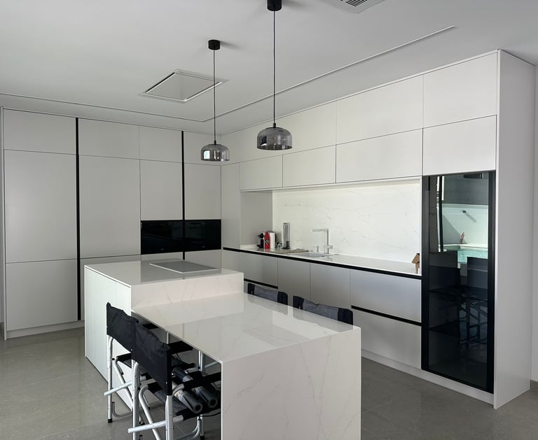 Cocina moderna blanca con isla y sillas altas.