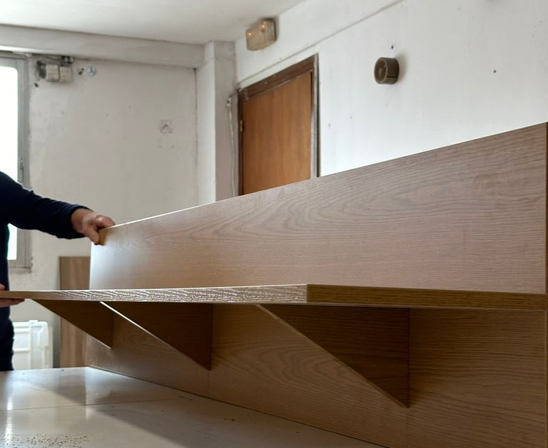 Persona instalando estantería de madera en la pared.