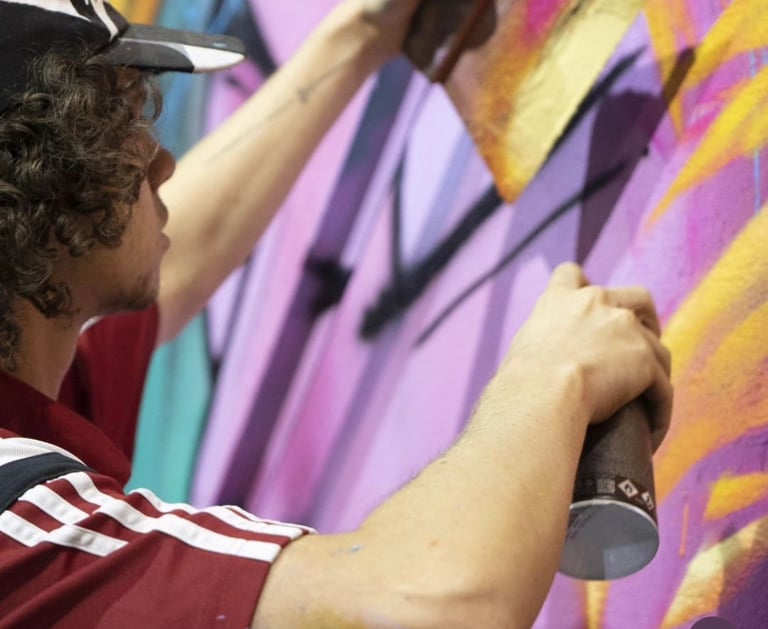 un homme avec une casquette entrain de peindre un graff