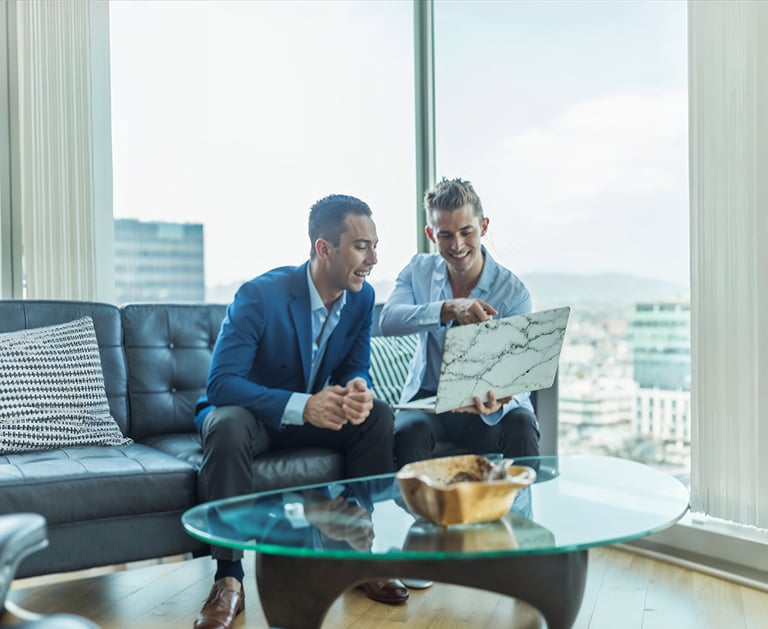 two men sitting on a couch in a living room