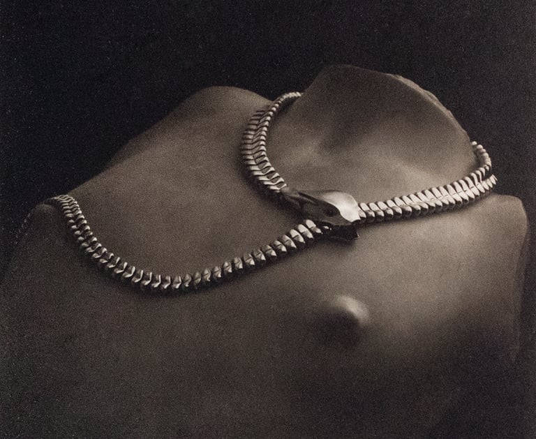 Vintage surrealist photography of a metallic snake necklace by Tiffany & Co on a torso sculpture.