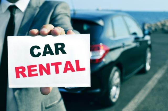 a man in a suit and tie holding a car rental sign