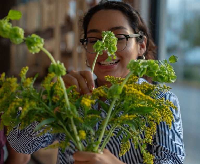 Florista sonriente arreglando un ramo de flores silvestres frescas amarillas y verdes en una tienda.