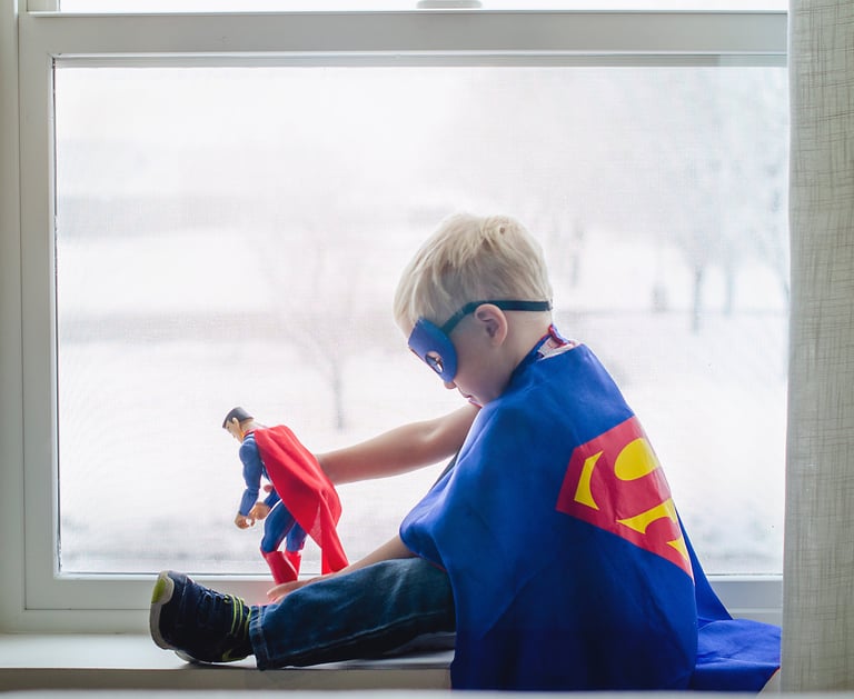 Super hero kid playing with a super hero toy