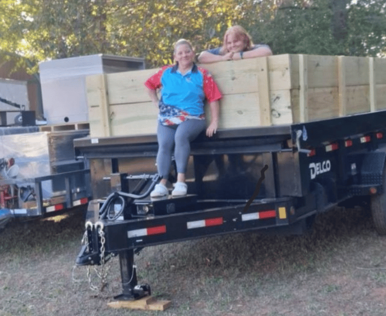 Owner, Sherieanne Skinner and daughter, Lily, standing up on her dump trailer