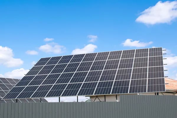 Fotografía inclinada desde abajo de paneles solares en color azul en el pasto al aire libre durante 