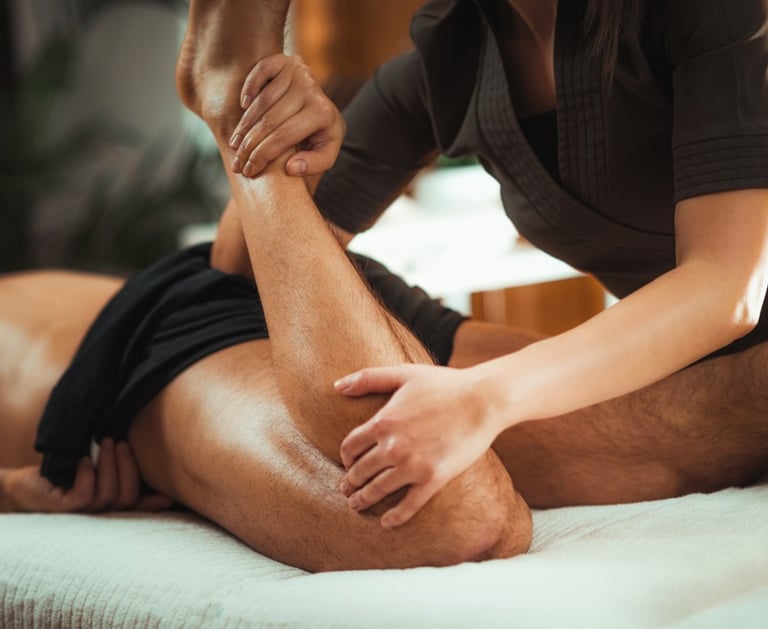 Massage therapist performing sports massage on male