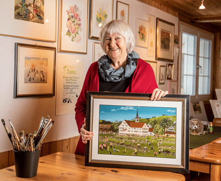 a woman holding a picture of a painting of a house