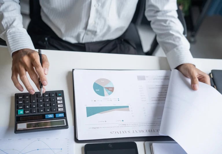 Person analyzing financial reports with calculator and charts