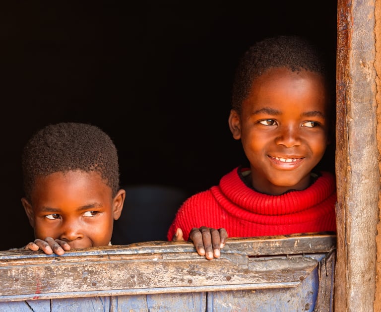 two young boys are looking out of a window