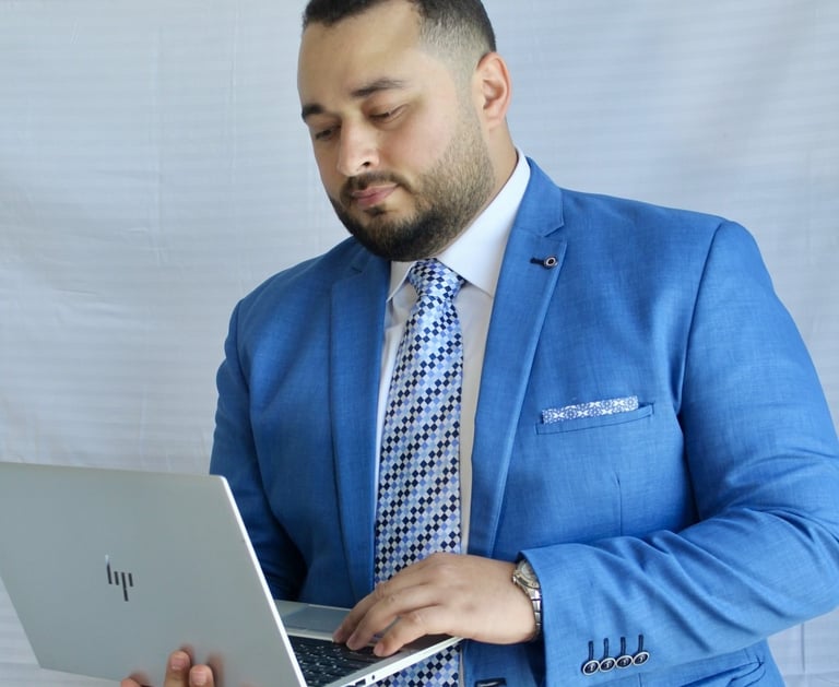 a man in a blue suit and tie is holding a laptop