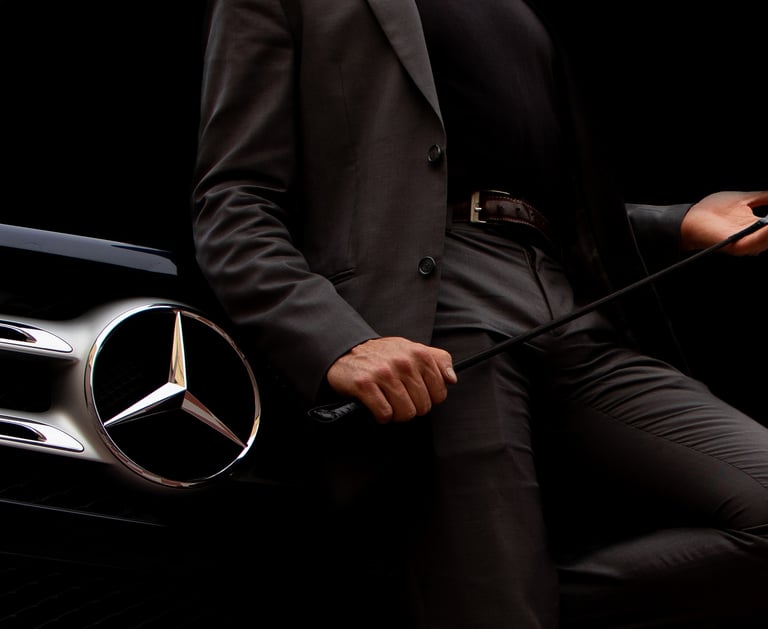 Homem de terno e gravata sentado diante de uma Mercedes, simbolizando sucesso e poder executivo