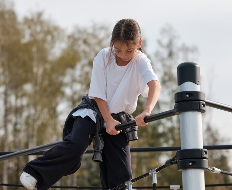 Fille grimpant sur une structure Kenguru Pro Kids Active Play en extérieur.