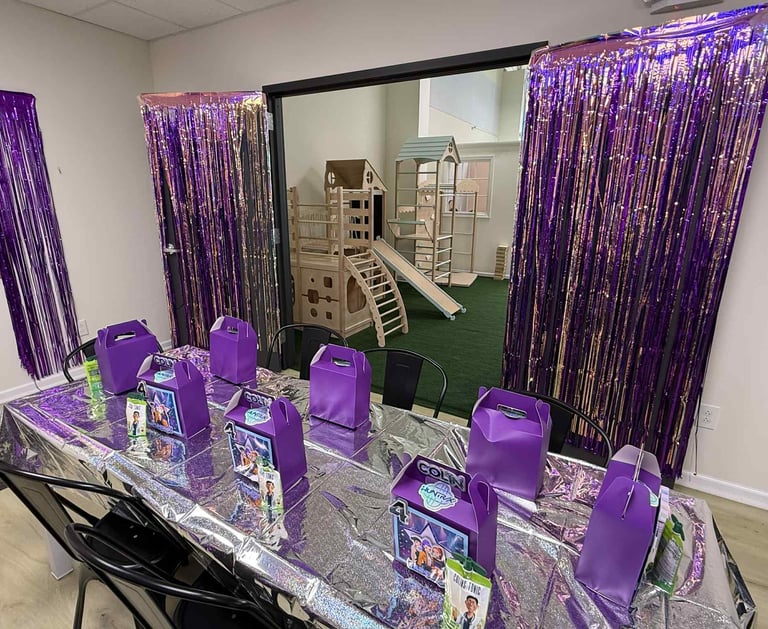 a party table with purple bags of candy and purple bags